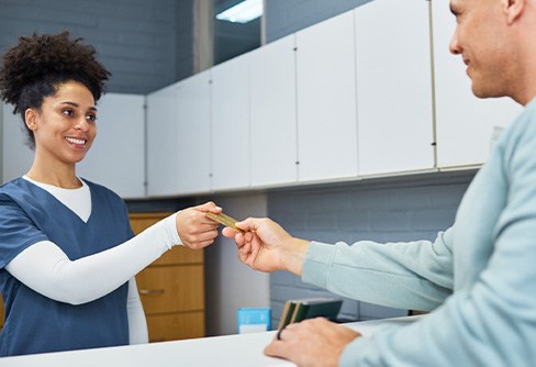 Woman at checkout counter accepting man’s payment card