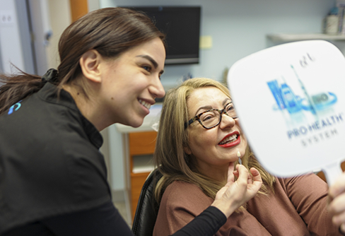 Dental patient looking at her new smile in a mirror