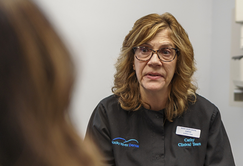 Dental team member talking to a patient in the dental chair