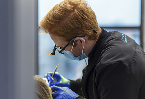 Dentist wearing dental binoculars while treating a patient