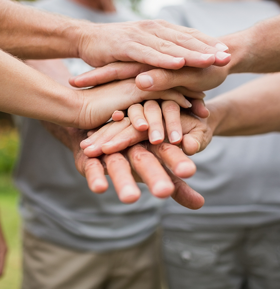 Circle of people putting their hands together in the middle