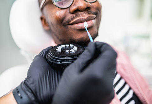 Dentist holding a veneer to a smiling patient