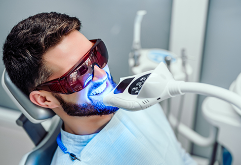 Man in dental chair getting his teeth professionally whitened