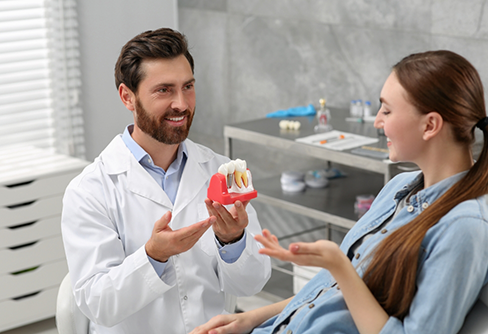 Dentist showing a patient a model of a dental implant