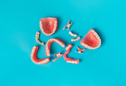 Full and partial dentures arranged against blue backdrop