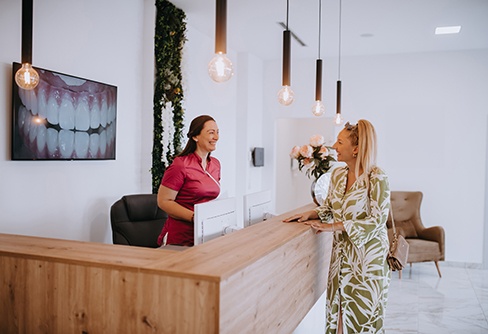 Dental receptionist smiling at patient in lobby