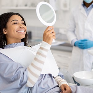Woman smiling at reflection in handheld mirror