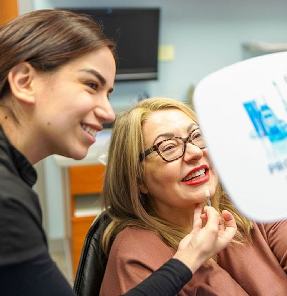 Rocky River dental patient admiring her smile in a mirror