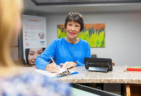 Woman filling out paperwork at dental office reception desk
