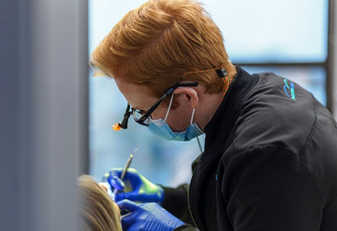 Dentist wearing dental binoculars while treating a patient