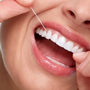 A closeup of a woman flossing between her teeth
