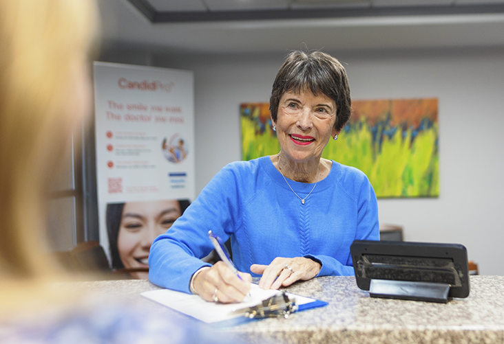 Woman taking a clipboard from a dental office receptionist