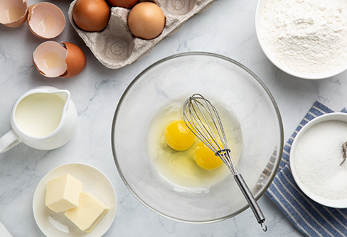 Bowl with two eggs and a whisk