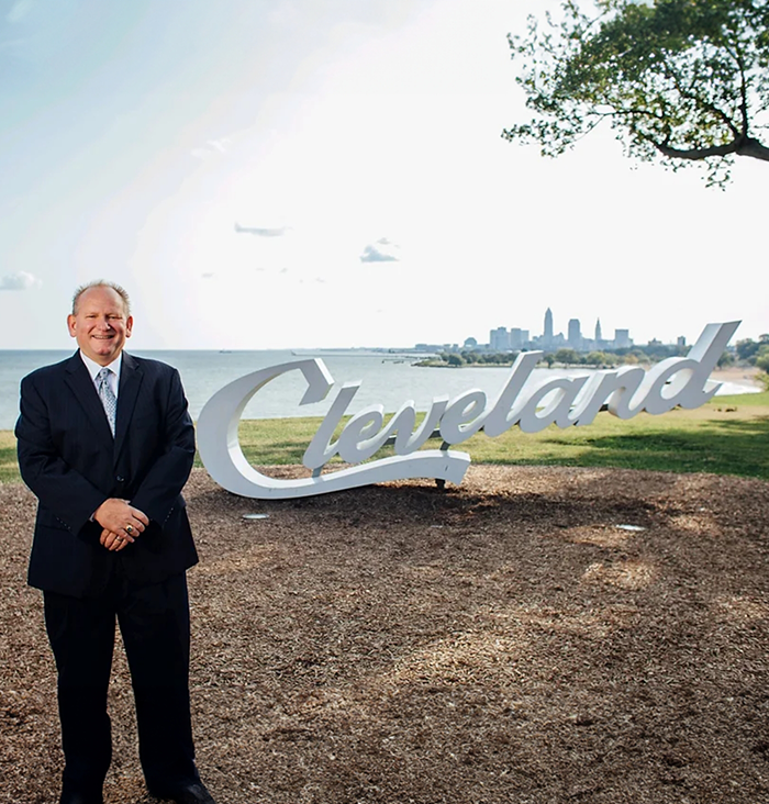 Rocky River dentist Doctor William L Farr smiling next to a small statue that says Cleveland