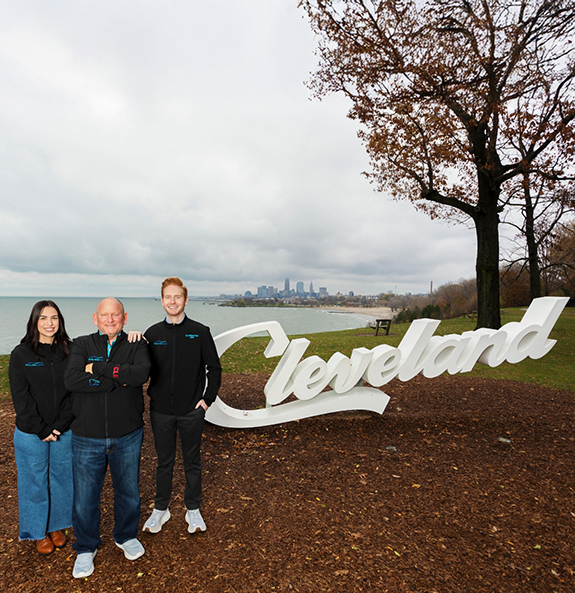 Three smiling Rocky River dentists standing next to a small statue that says Cleveland