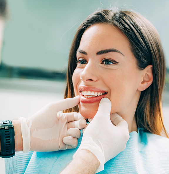 Woman smiling at her dentist after replacing missing teeth in Rocky River