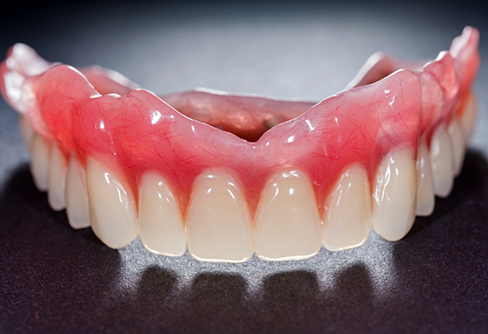 Full upper denture against gray background