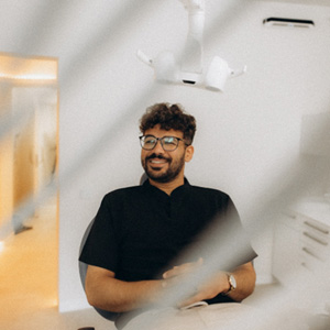 Patient with black glasses smiling in treatment chair