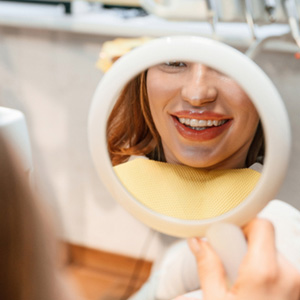 Patient with clear aligners smiling at reflection in mirror