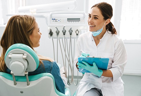 Dentist smiling at patient while taking notes