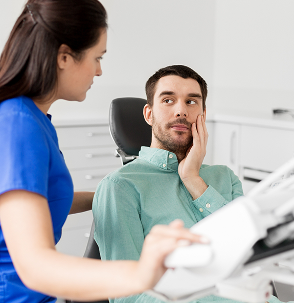 Dental patient holding his cheek in pain before root canal treatment in Rocky River