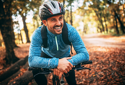 Smiling man riding a bike through a forest