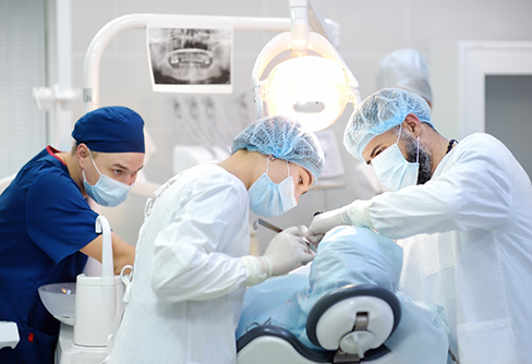 Three dental professionals performing a dental procedure on a patient