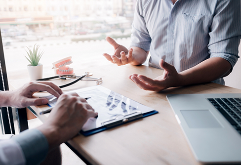 Dental patient sitting at table with dentist having discussion