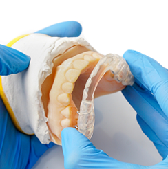 Dentist holding a clear tray over a model of a row of teeth