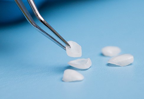 Veneer from a pile of several on a blue surface being grasped by tweezers