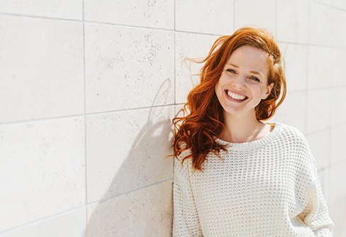 Woman smiling by a white wall