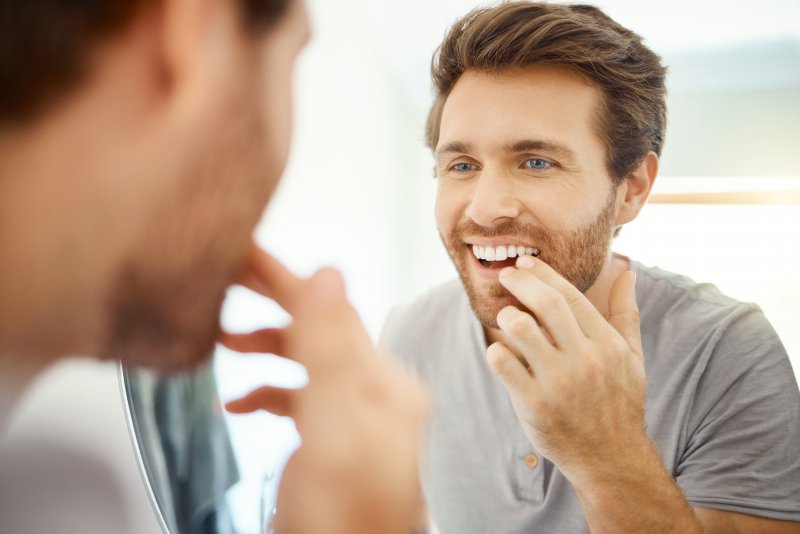 Patient smiling in mirror after cosmetic dentistry