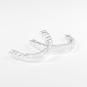 Two clear aligners hard to see against a white background